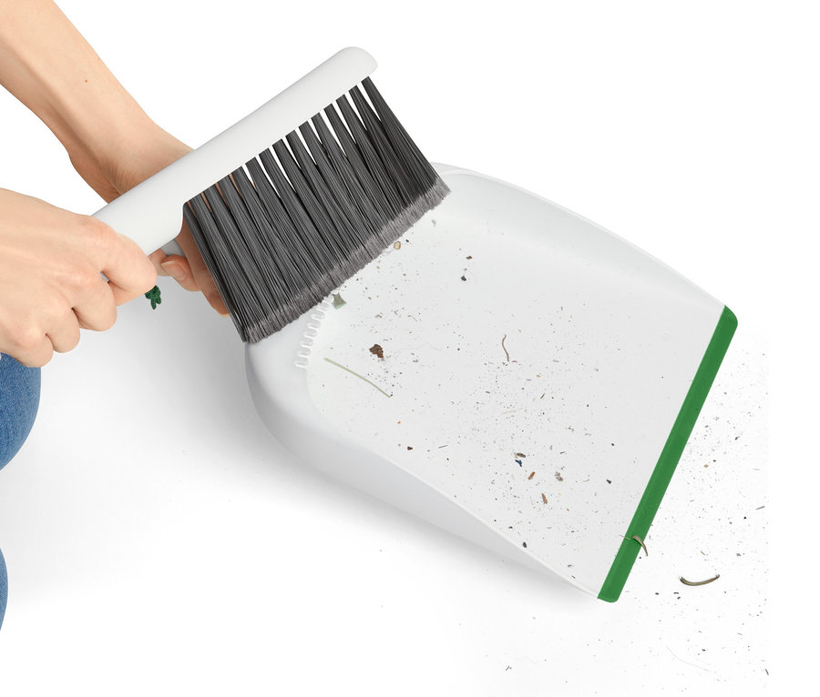 Hände kehren mit Handkehrer und Schaufel Schmutz in die Schaufel.