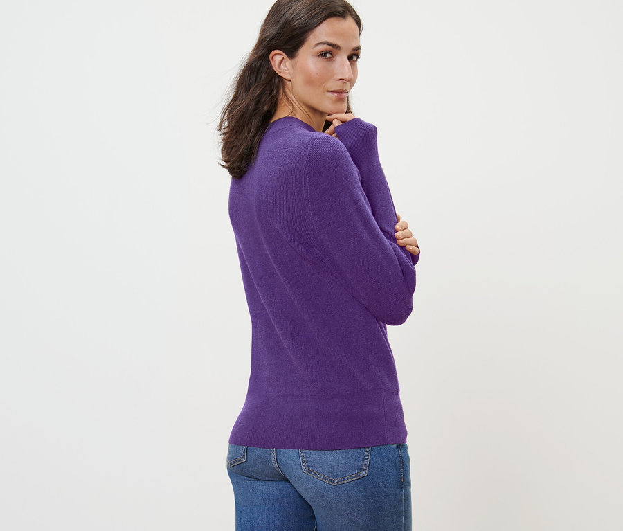 Frau posiert in einem Feinstrickpullover.