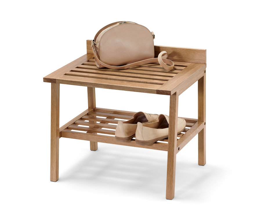 Eine Handtasche liegt auf der obersten Ablagefläche eines Hockers mit breiten Ablageflächen, unten stehen Schuhe.