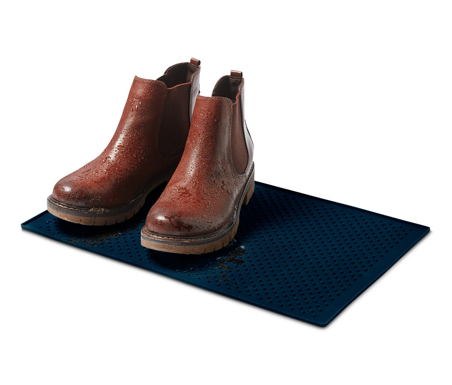 Zwei braune Lederstiefel stehen auf einem blauen Futternapf-Untersetzer.