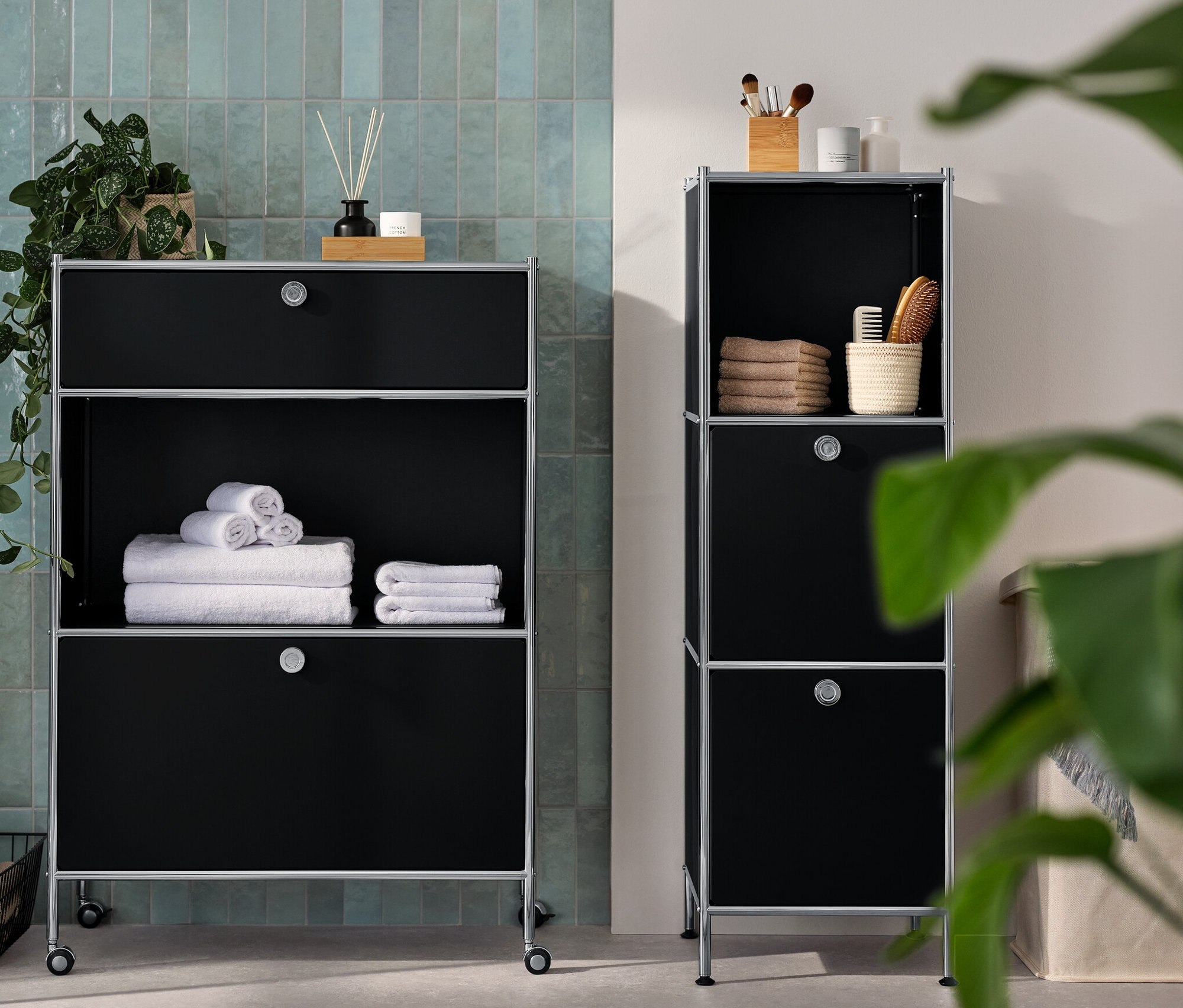 Eine schmale Kommode Metall »CN3« mit 2 Klappenfächern und eine Kommode Metall »CN3« mit 1 Schublade und 1 Klappenfach stehen im Badezimmer. Auf den Kommoden liegen Handtücher und Accessoires.