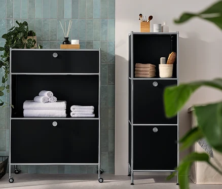 Eine schmale Kommode Metall »CN3« mit 2 Klappenfächern und eine Kommode Metall »CN3« mit 1 Schublade und 1 Klappenfach stehen im Badezimmer. Auf den Kommoden liegen Handtücher und Accessoires.