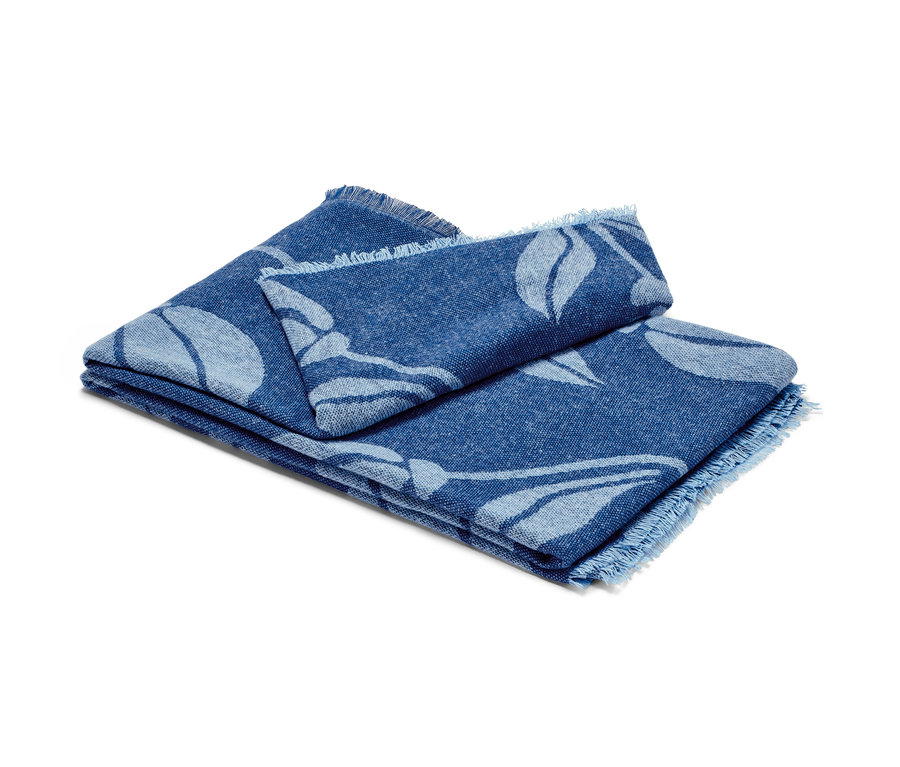 Zusammengelegte Wohndecke mit Fransen und blauem Blumenmuster.