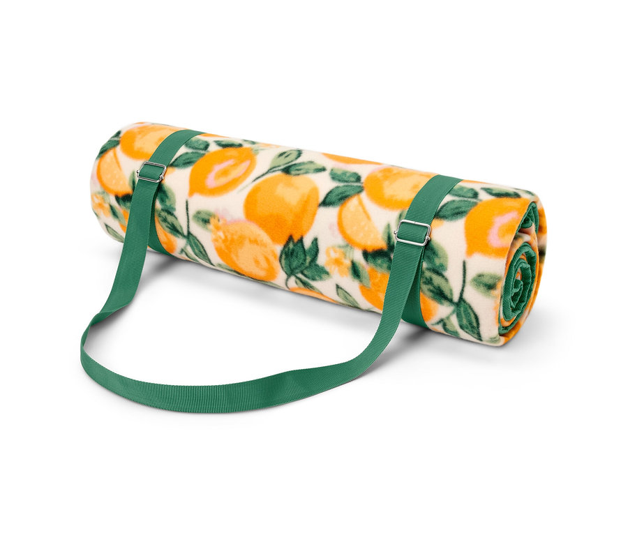 Eine zusammengerollte XL-Picknickdecke mit Orangenmuster und grünen Riemen.