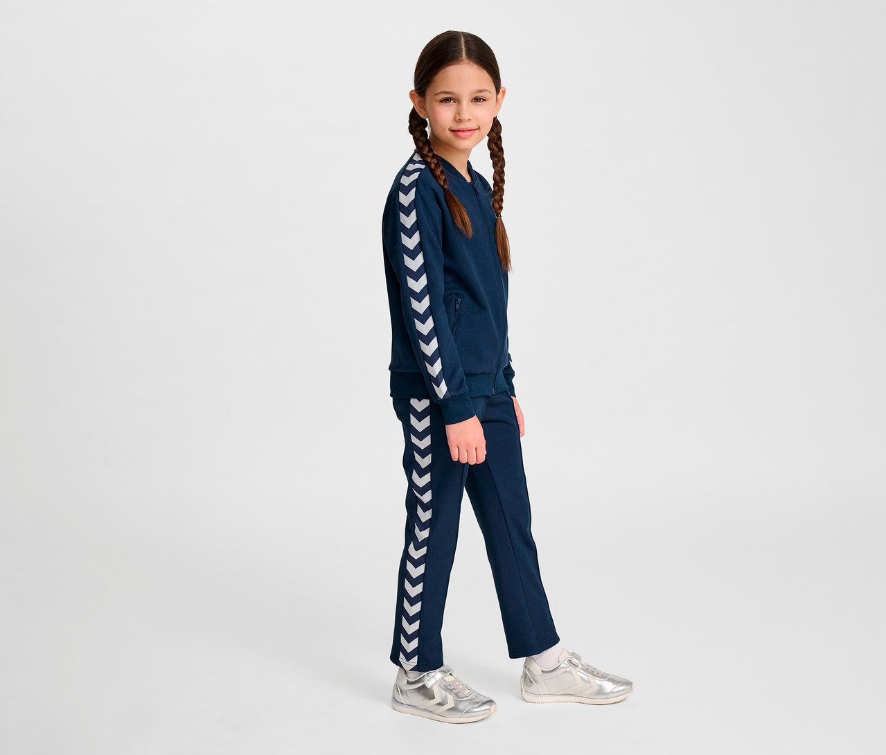 Mädchen trägt blaue Hummel HMLJR Archive Reg Poly Zip Jacket.