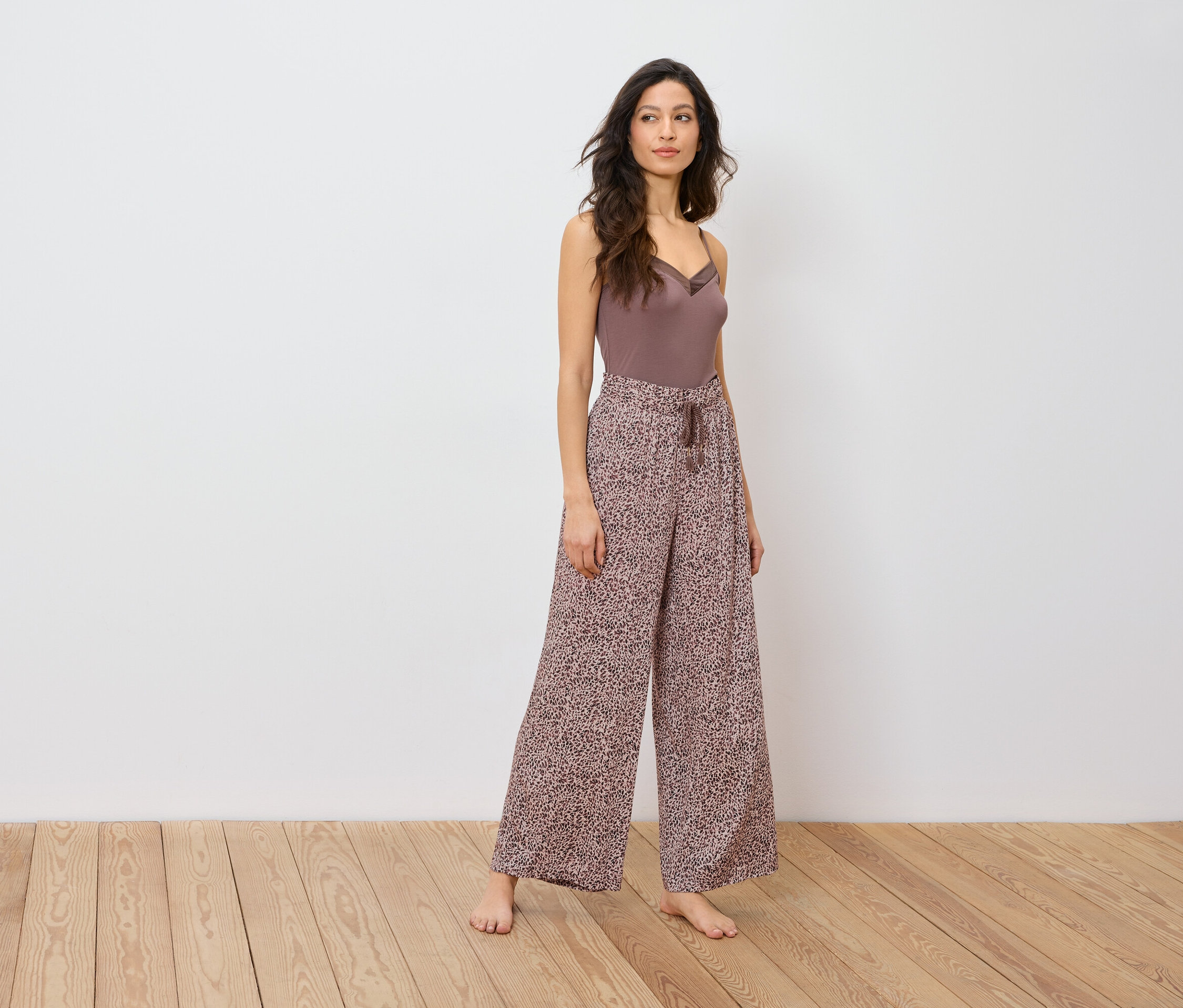 Frau posiert in braunem Top und weiter Hose mit Animal-Print.