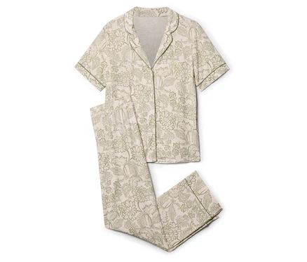 Ein zweiteiliger Pyjama mit hellrosafarbenem Grund und grünem Blumenmuster liegt auf einem weißen Hintergrund.
