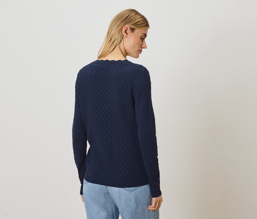 Frau trägt einen marineblauen Pullover und Jeans.