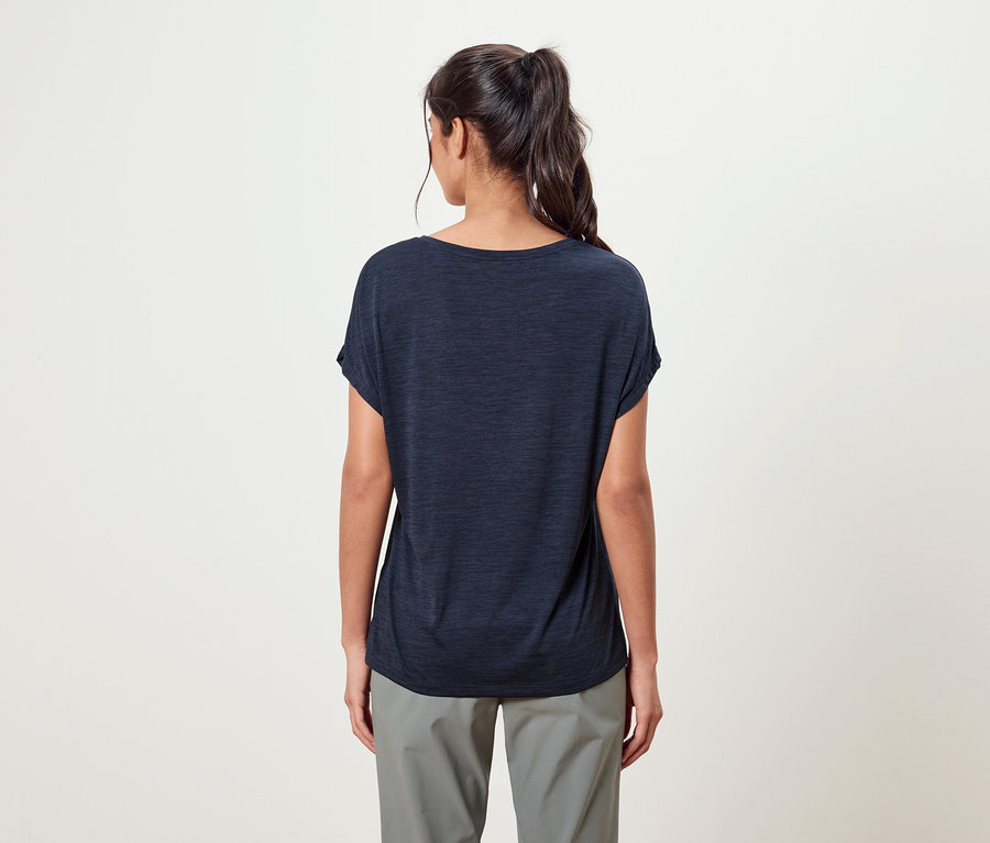 Rückansicht einer Frau mit Pferdeschwanz, die ein marineblaues T-Shirt und eine graue Hose trägt.