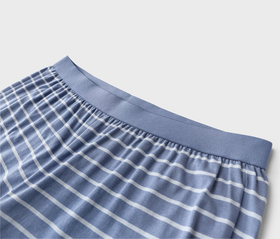Nahaufnahme von blau-weiß gestreiften Pyjamahosen mit blauem Gummibund.