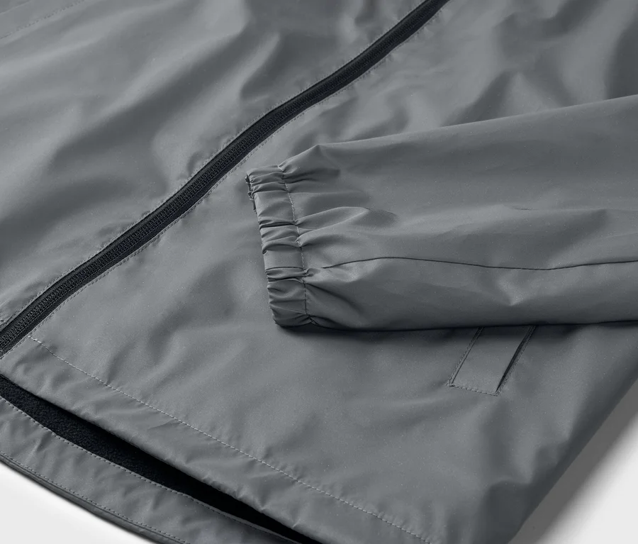Nahaufnahme einer grauen Jacke mit Reißverschluss und elastischen Ärmelbündchen.