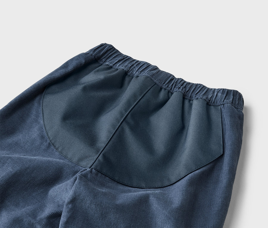 Detailaufnahme einer blauen Kordhose mit elastischem Bund und aufgesetzter Gesäßtasche.