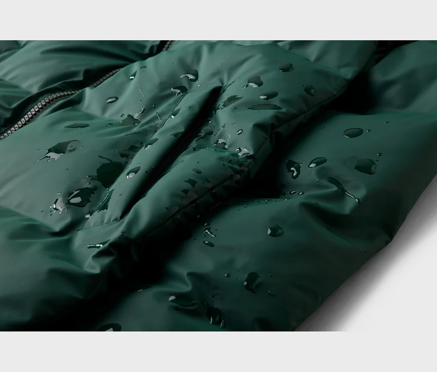 Dunkelgrüne, wasserabweisende Steppjacke mit Reißverschluss, auf der Wassertropfen abperlen.