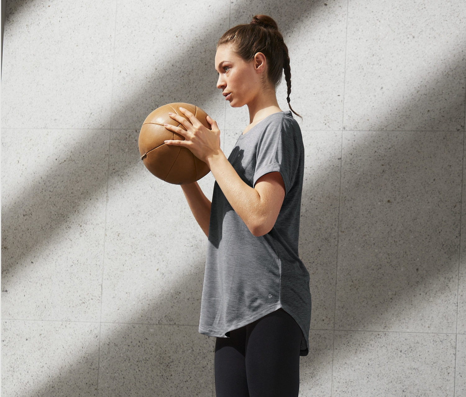 Frau hält Medizinball und geht Stufen hoch. Sie trägt ein Longshirt.