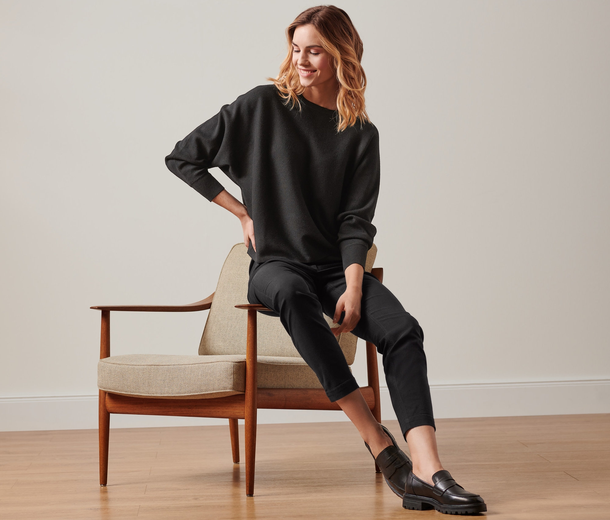 Frau sitzt auf einem Stuhl und trägt eine konfektionierte Bengalinhose in Schwarz.