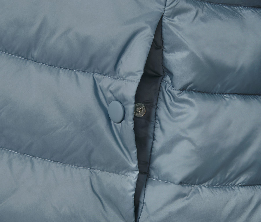 Detail einer Steppjacke mit Tasche und Druckknopf.
