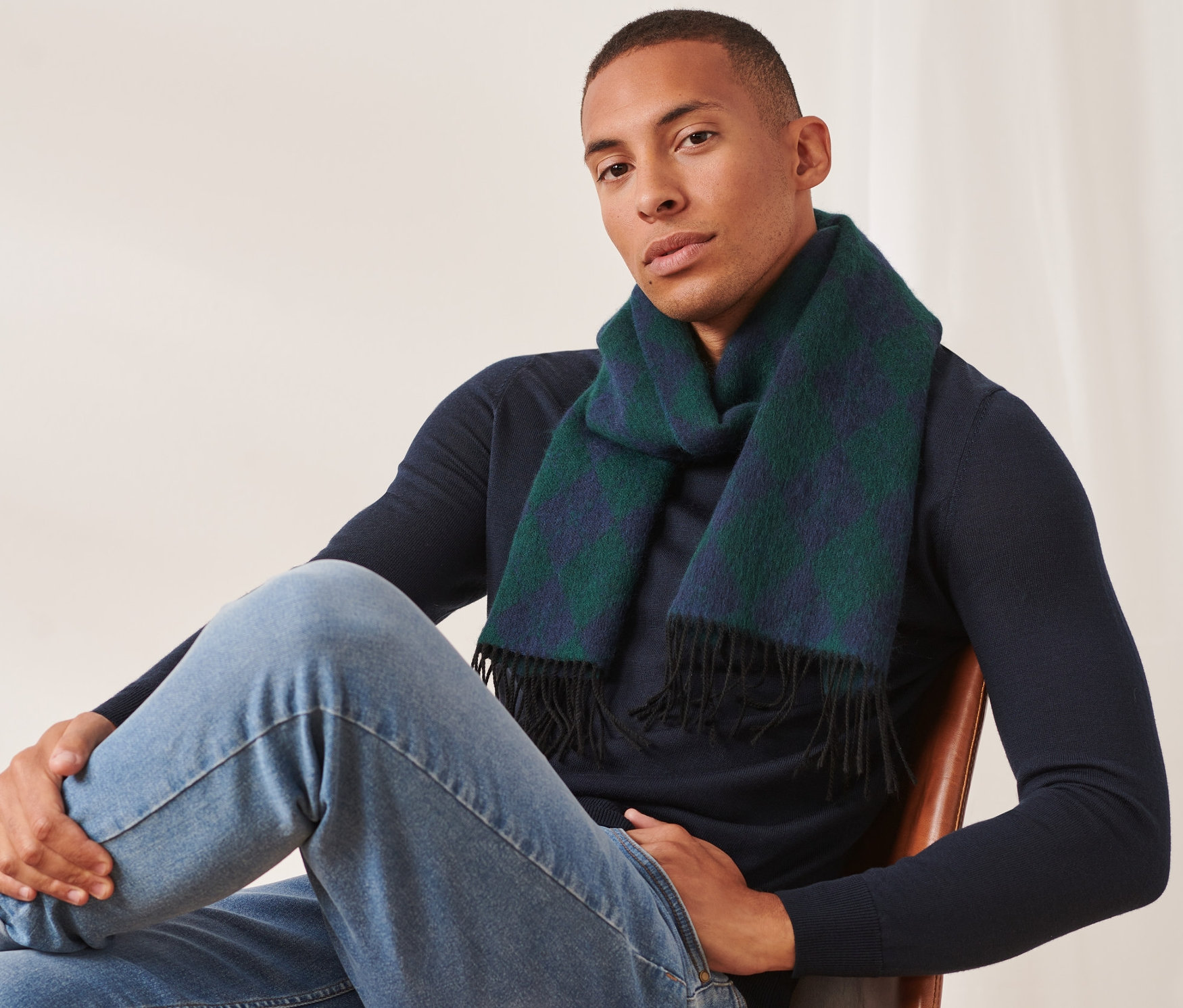 Mann sitzt auf einem Stuhl und trägt einen Wollschal.