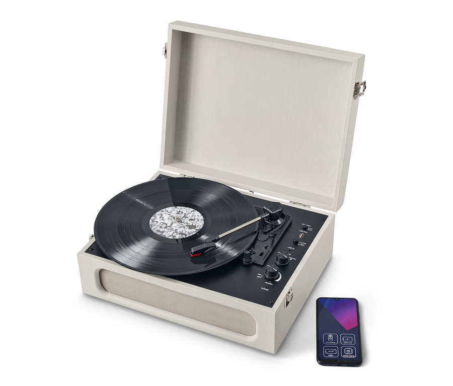 Ein beiger, tragbarer Retro-Plattenspieler mit Bluetooth®-Funktion mit geöffnetem Deckel und Schallplatte. Neben dem Plattenspieler befindet sich ein Smartphone.