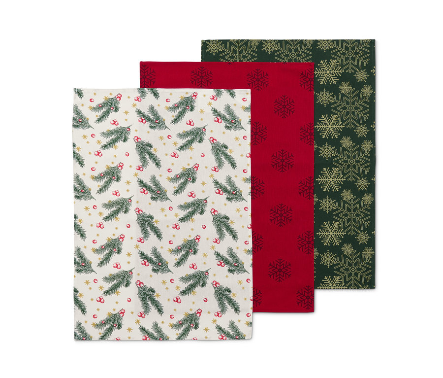 Drei Geschirrtücher: Eines mit Tannenzweigmuster, eines rot mit Schneeflocken, eines grün mit goldenen Schneeflocken.