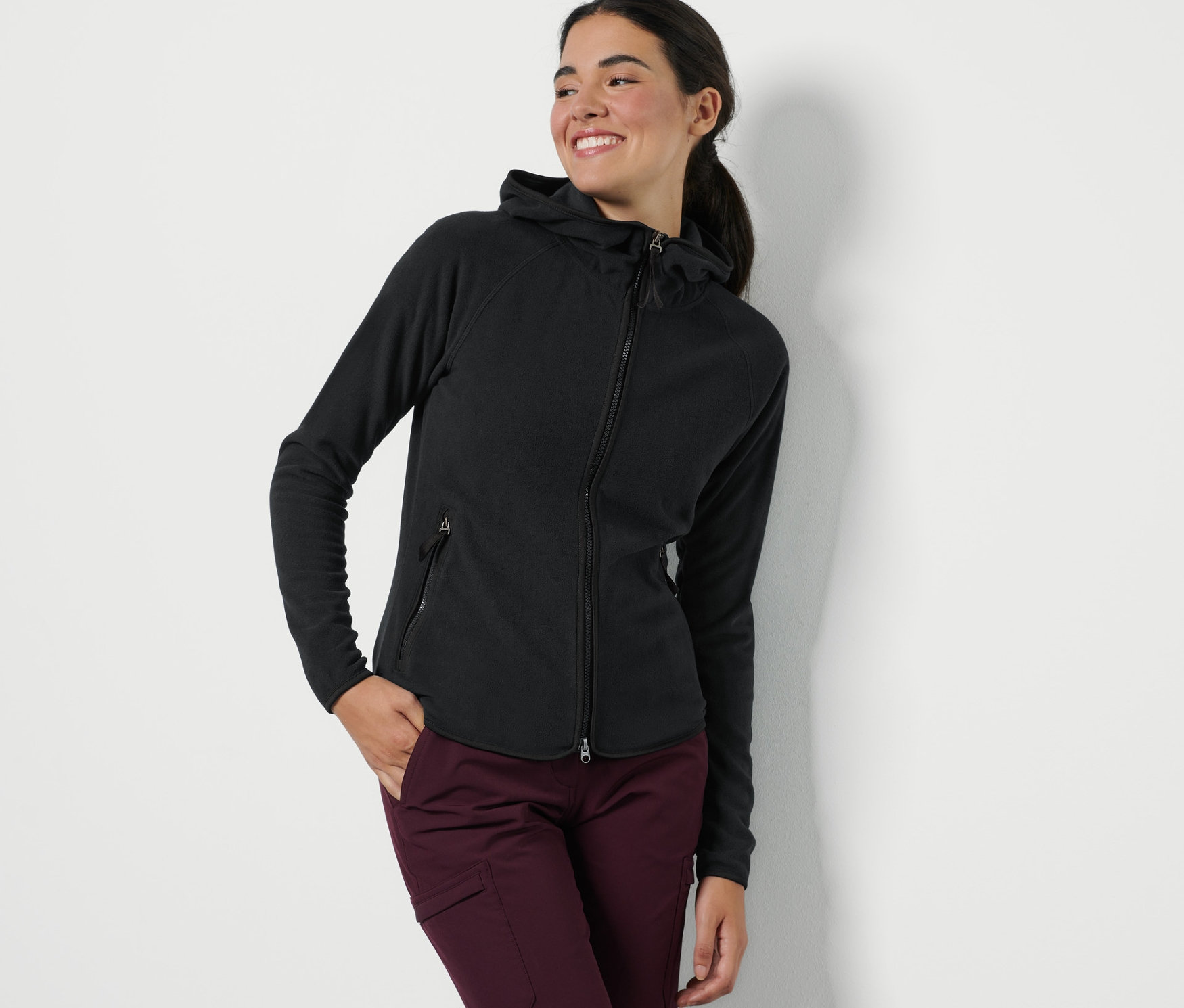 Frau posiert in einer schwarzen Kapuzen-Fleecejacke.