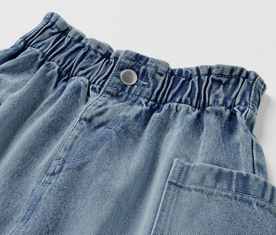 Detailansicht eines Kinder-Paperbag-Jeansrocks mit Knopfverschluss und Taschen.