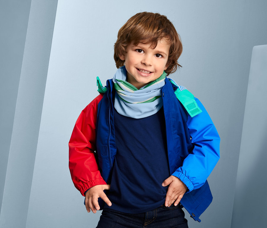 Lächelnder Junge mit braunen Haaren, der in die Kamera schaut und ein blau-grünes, recyceltes Multifunktionstuch trägt.