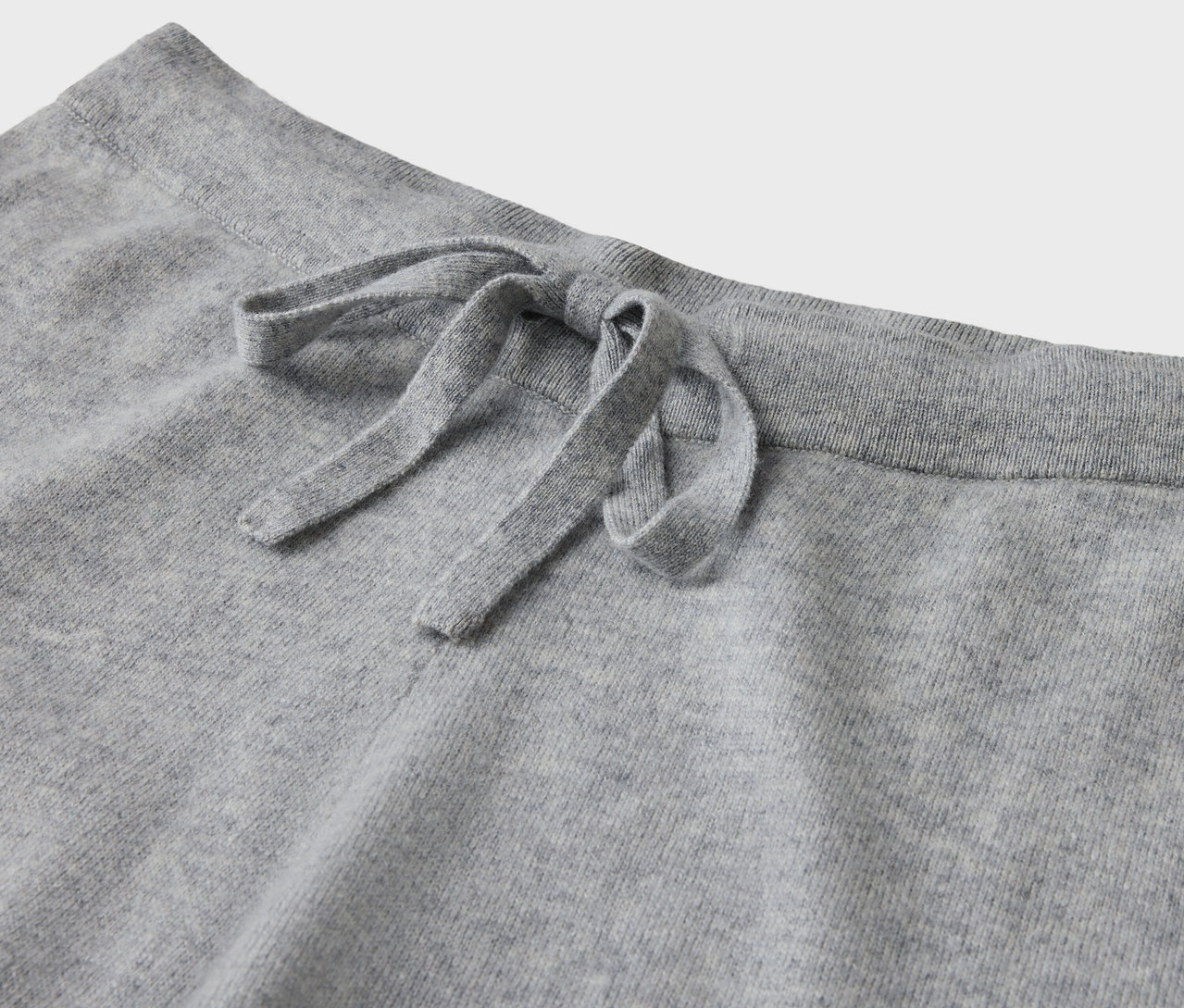 Detail einer grauen Jogginghose mit Kordelzug.