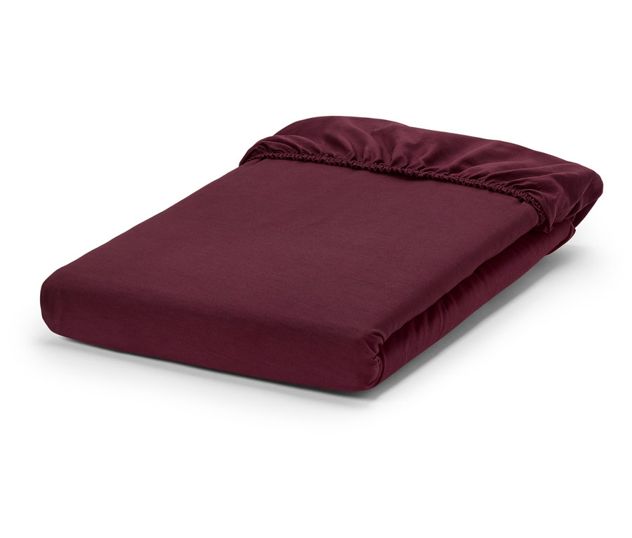 Ein burgunderrotes Spannbettlaken, gefaltet auf einem weißen Hintergrund.