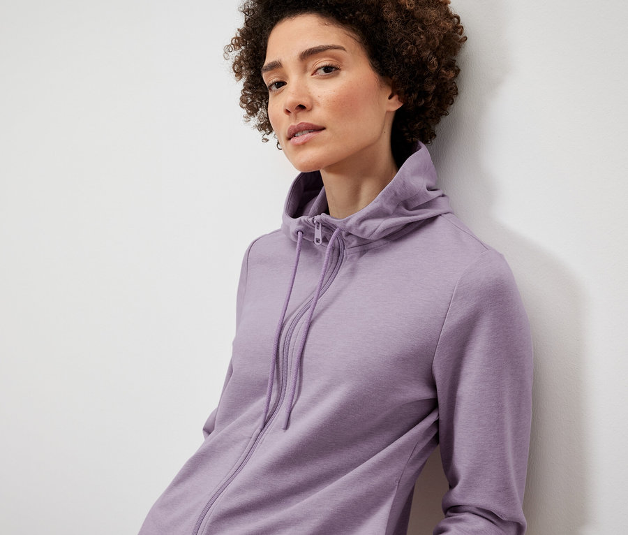 Frau posiert in lila Sweatjacke.