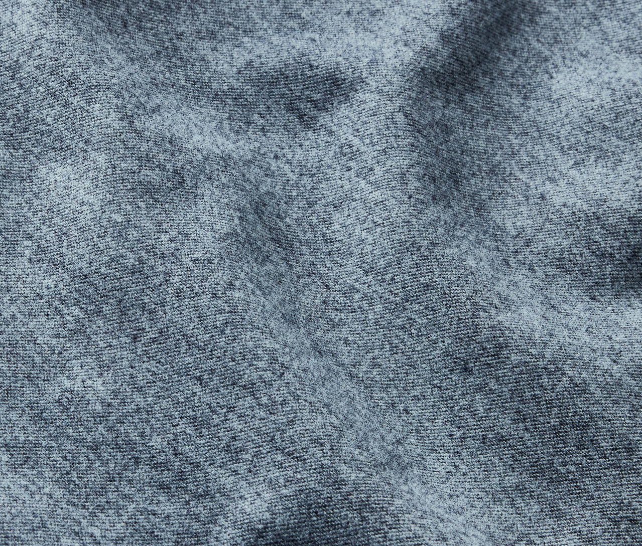 Detailaufnahme einer grauen Stofftextur mit feinem Muster und Falten.