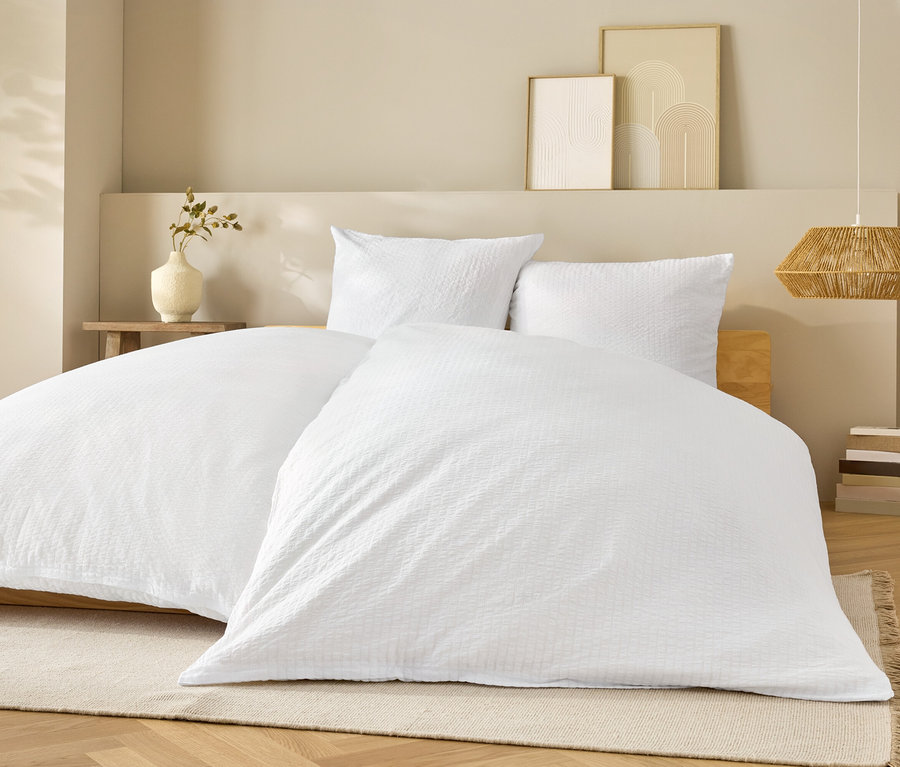 Weisse Bettwäsche auf einem Bett mit weissen Kissen.