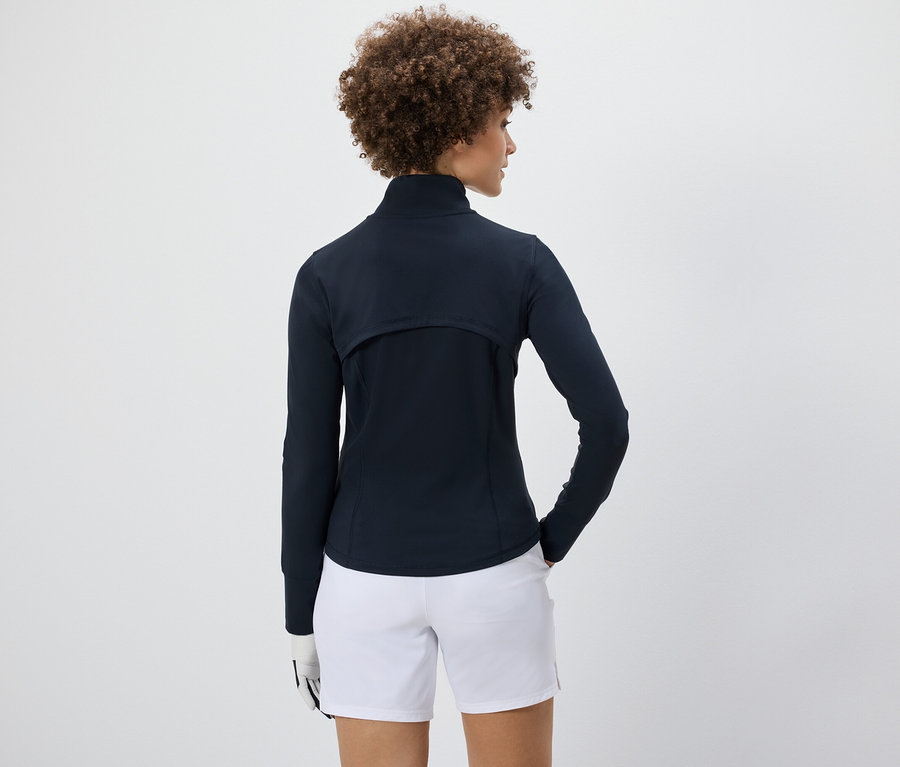 Frau trägt eine Funktionsjacke und weiße Shorts.