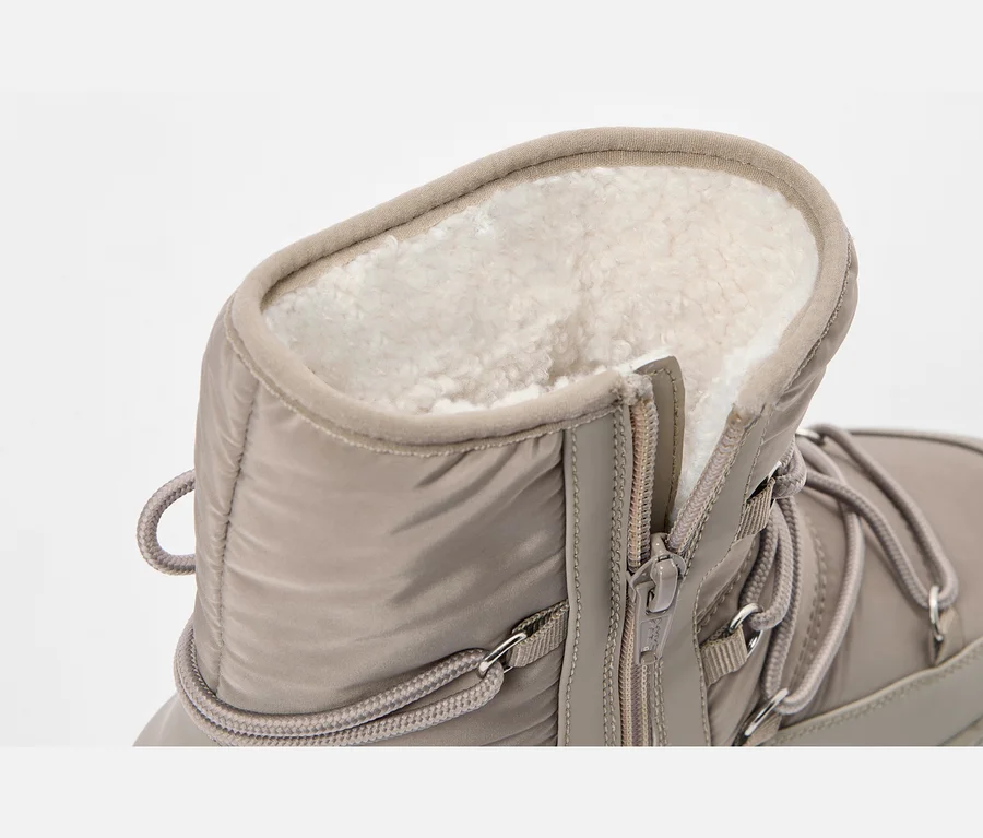 Nahaufnahme eines beigefarbenen Winterstiefels mit flauschigem Innenfutter, seitlichem Reißverschluss und Schnürsenkeln.