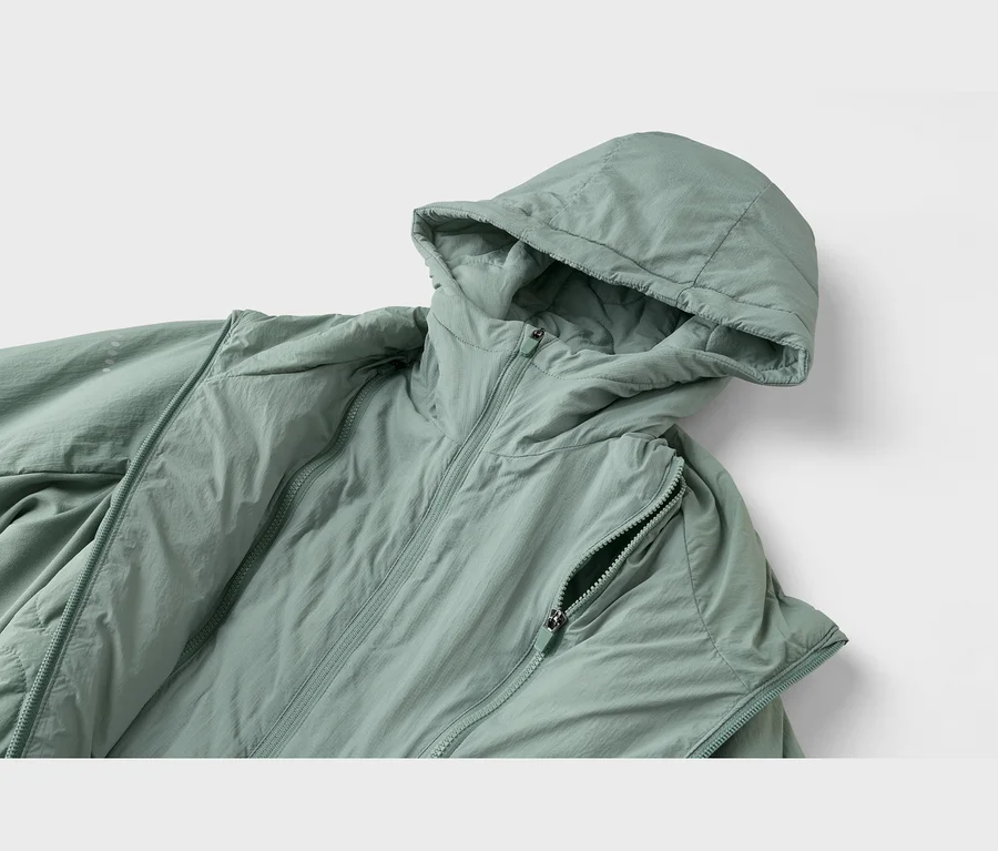 Nahaufnahme einer hellgrünen Kapuzenjacke, teilweise geöffnet, mit Hauptreißverschluss und einer kleineren Reißverschlusstasche.