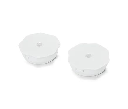 Zwei runde, weiße Puck-Leuchten liegen auf einer weißen Oberfläche.