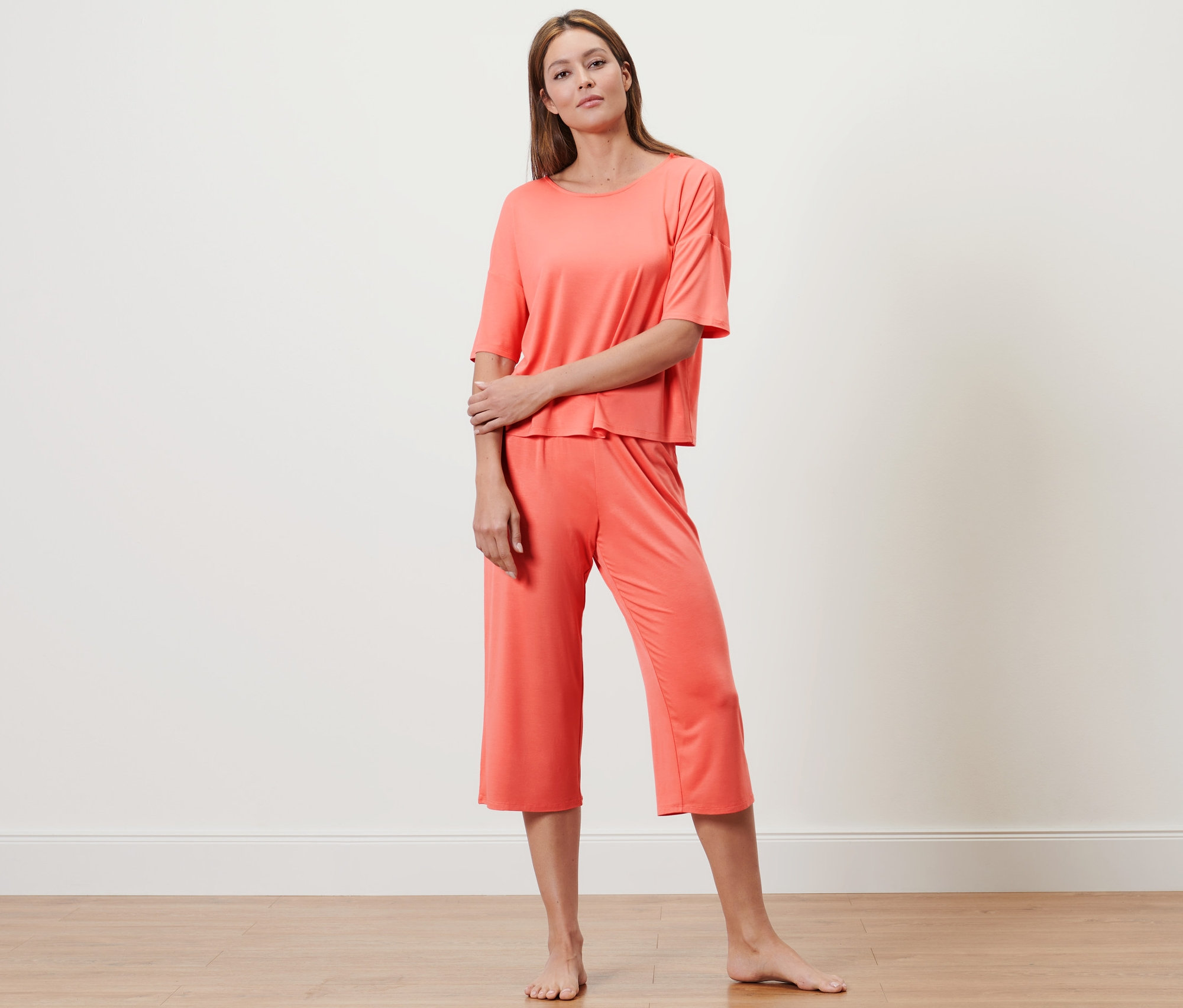 Frau posiert in einem lachsfarbenen 3/4-langen Pyjama.