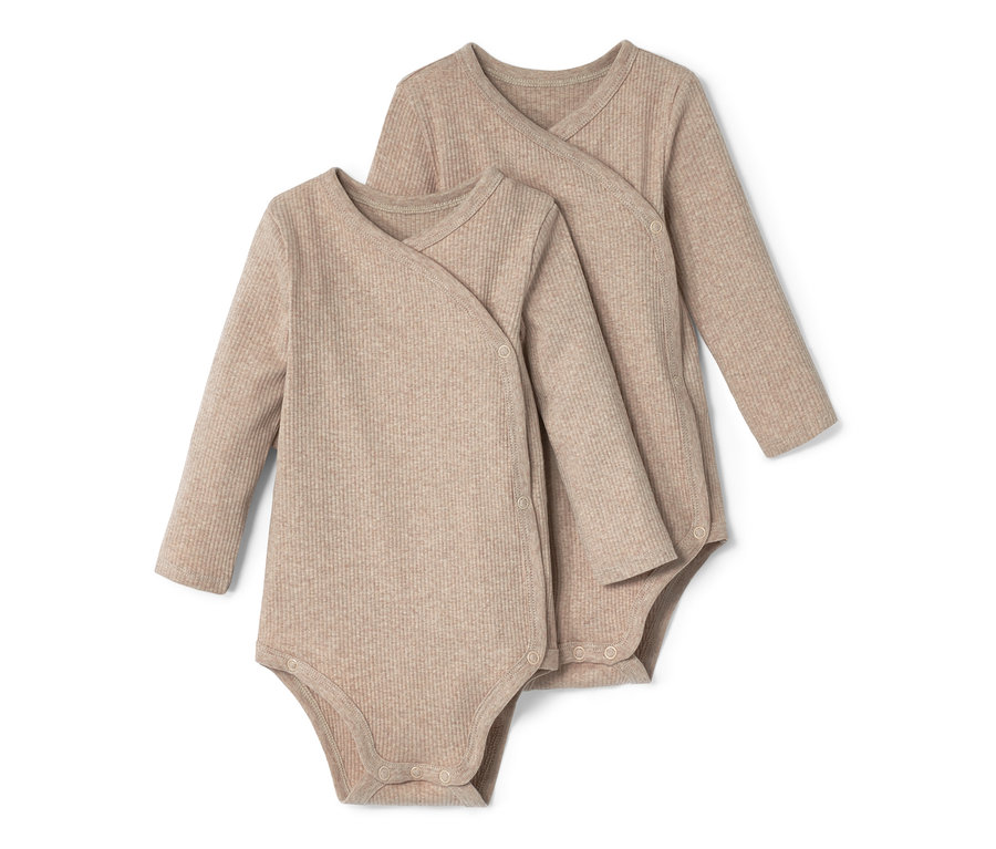 Zwei beige Baby-Langarmbodys liegen übereinander.