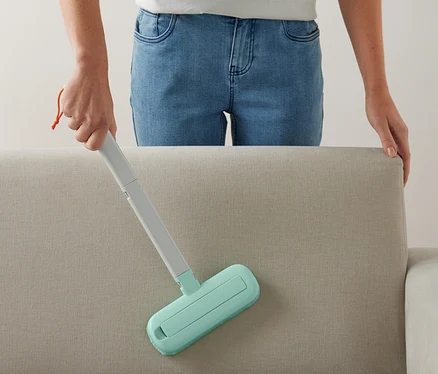 Frau reinigt Sofa mit 4-in-1-Textil-Sauberzauber.