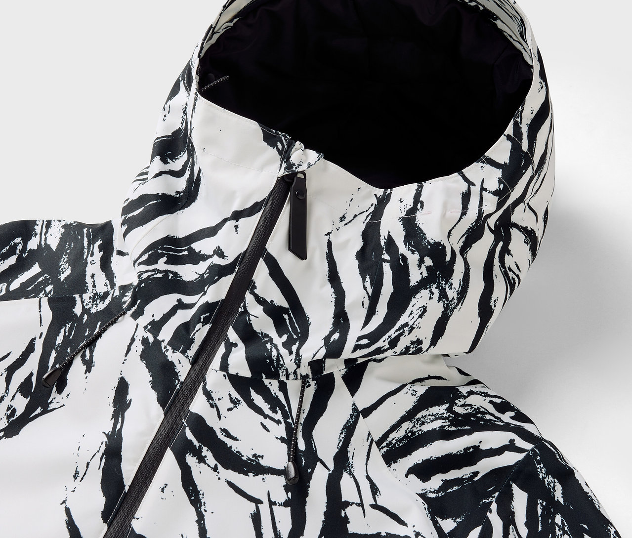 Detailansicht der Kapuze einer Jacke mit Zebra-Muster und schwarzem Reißverschluss.