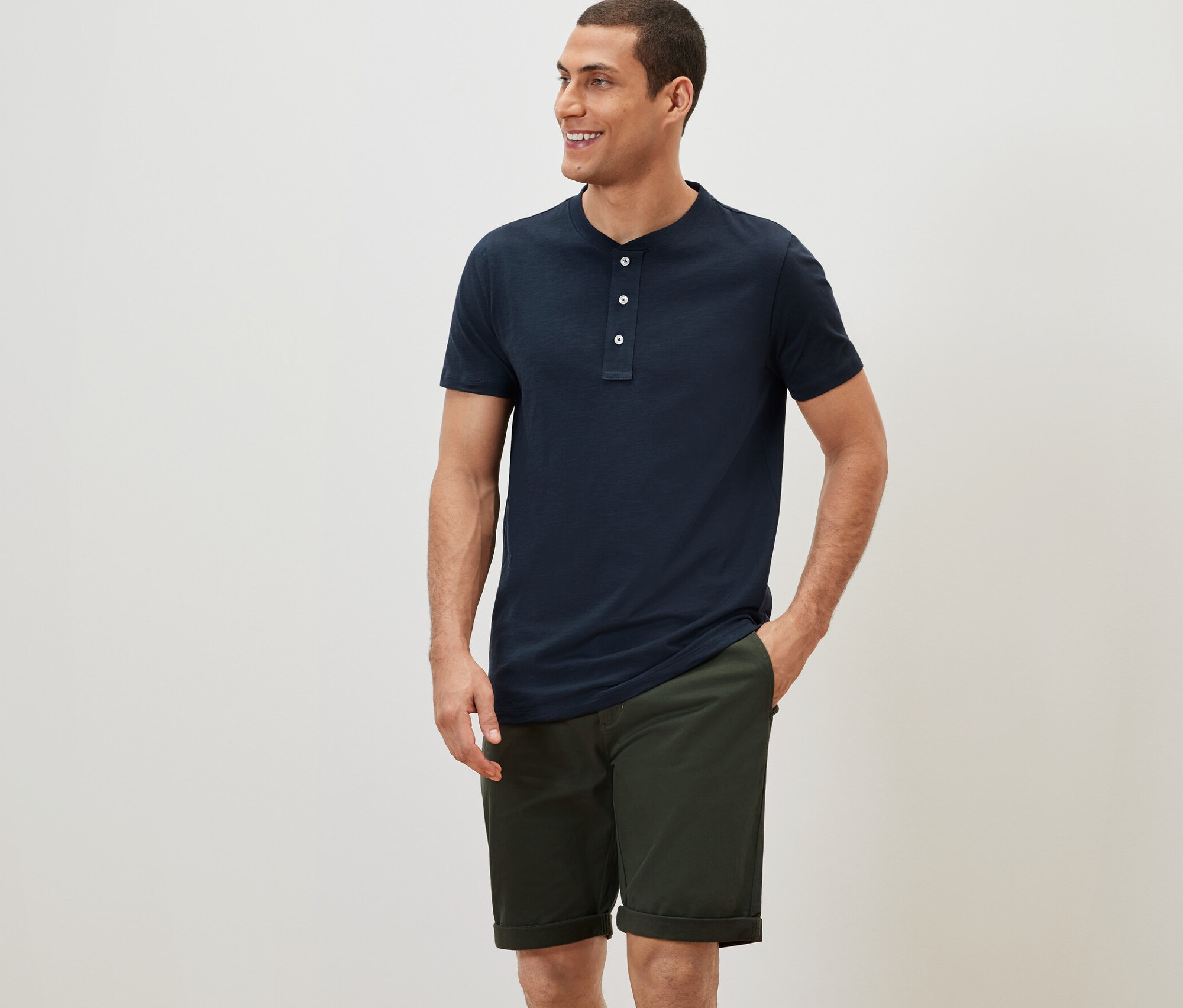 Mann in marineblauem Kurzarmhemd und Khaki-Chino-Shorts.