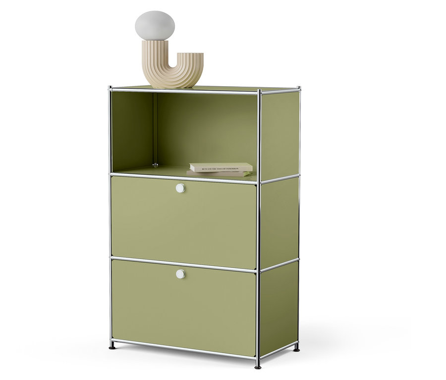 Grüner Schrank mit zwei Schubladen und einem offenen Oberboden, auf dem ein Buch liegt und eine dekorative Lampe steht.