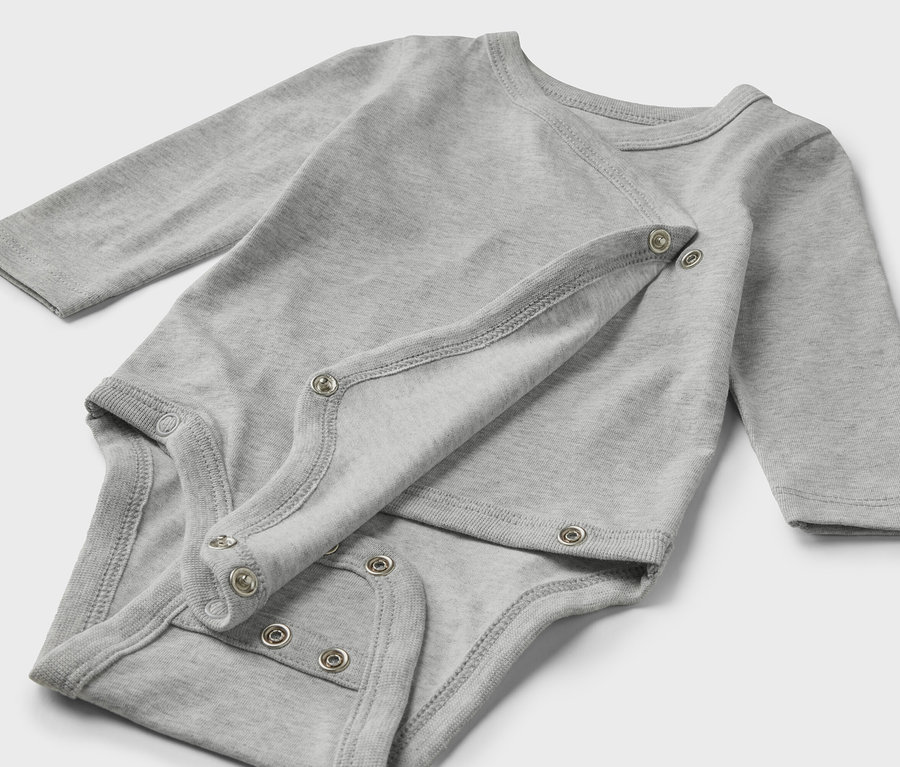 Ein grauer 5er-Pack Baby-Bodys mit Mitwachsfunktion liegt auf hellem Grund.