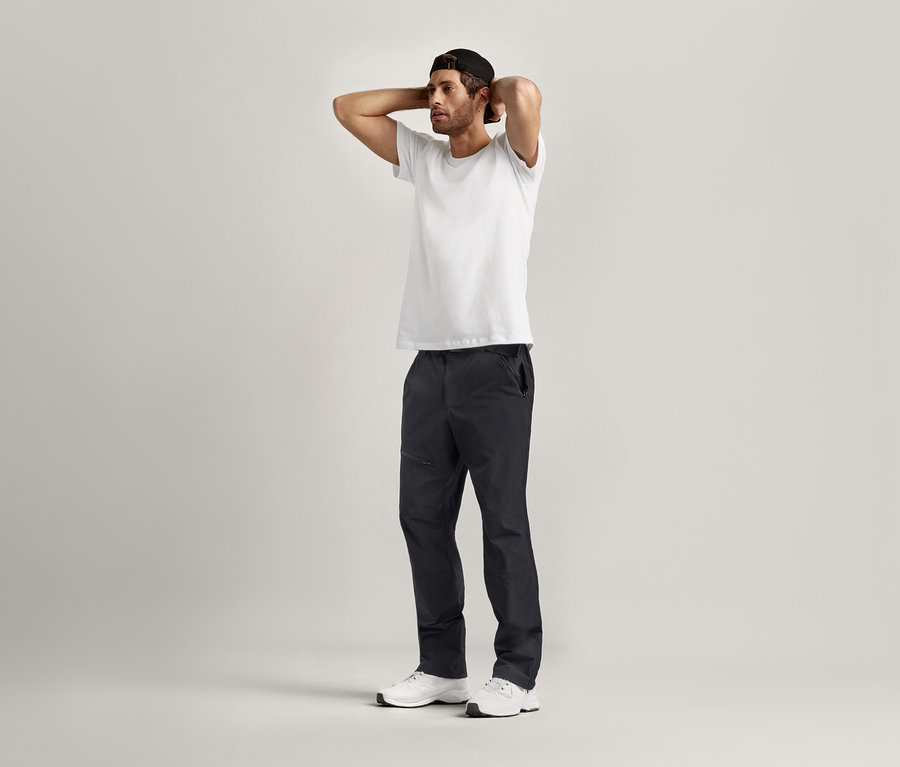 Mann posiert mit den Händen hinter dem Kopf und trägt ein weißes 2 T-Shirts mit Rundhalsausschnitt.