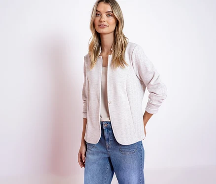 Frau mit Street One Jerseyblazer in Rosa und Jeans mit Händen in den Taschen.