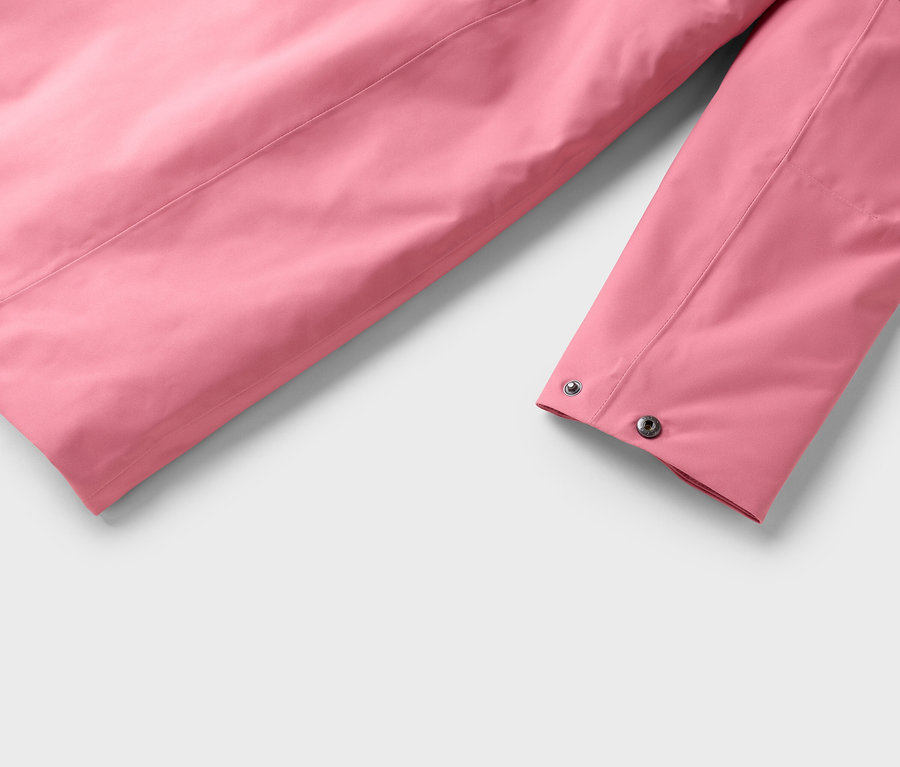 Detailaufnahme eines rosa Jackenärmels mit silbernen Druckknöpfen auf hellgrauem Grund.