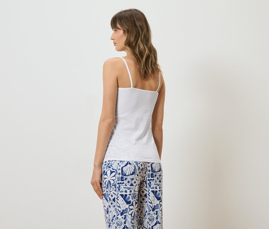 Frau von hinten in weißem Top und blau-weiß gemusterter Hose.