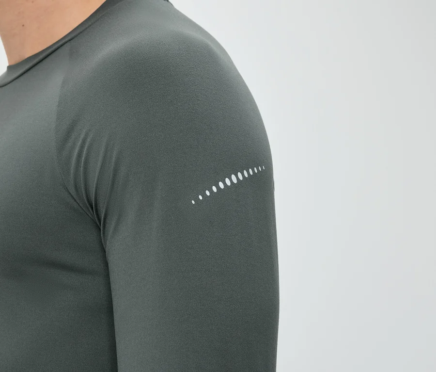 Nahaufnahme einer Person in einem grauen, langärmeligen Shirt mit einem weißen Punktmuster am Ärmel.