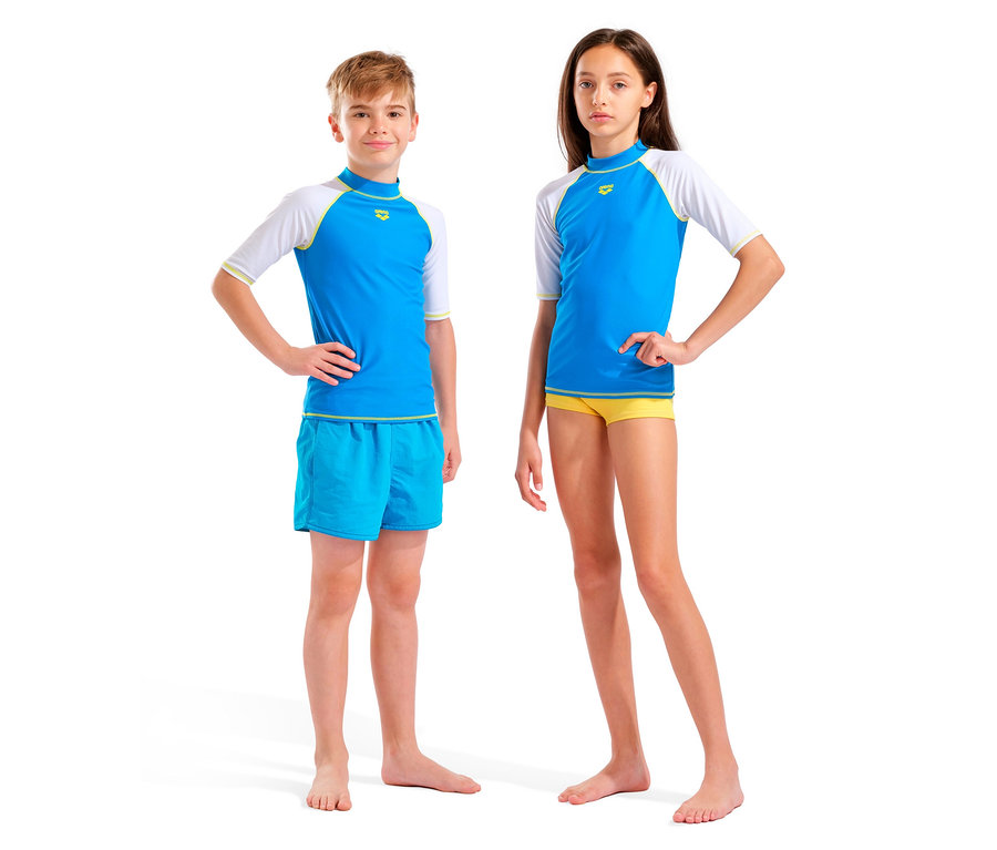 Ein Junge und ein Mädchen stehen barfuß vor einem weißen Hintergrund. Beide tragen blaue und weiße Oberteile und Badehosen.