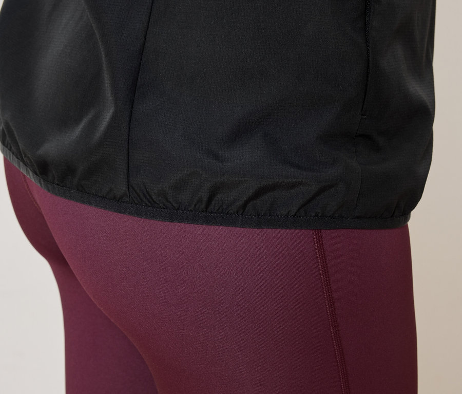 Nahaufnahme einer Person mit einer schwarzen Jacke und weinroten Leggings.