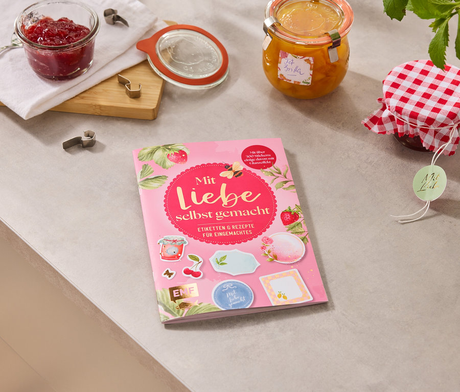 Auf einer Arbeitsfläche liegen Marmeladengläser und das Buch »Mit Liebe selbstgemacht«.